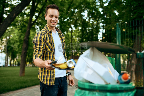 青年志愿者在公园的塑料垃圾桶里放志愿工作男清洁森林生态恢复活方式垃圾收集和回生态护理环境清洁青年志愿者在公园的塑料垃圾桶里放图片
