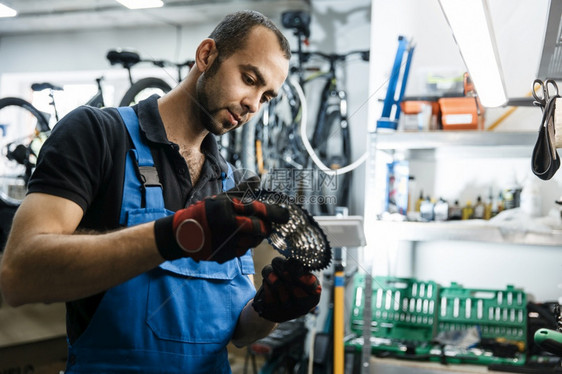 修理车间的自行人安装恒星磁带修理周期有制服问题的机械师专业自行车修理服务车间的自行修理人安装磁带图片