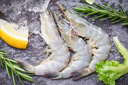 海产食品餐厅冰冻的生虾配有迷香成分药草和烹饪海鲜香料的木制剪板上新鲜虾图片