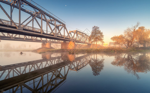 美丽的铁路桥和秋天日出时雾中的河流铁路站工业景观水道路雾树木的反射秋天大雾中的蓝交通美丽的铁路桥和秋天雾中河流背景图片