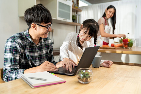 笔记本工作而母亲在厨房做饭家工作与新冠19隔离幸福家庭团圆概念背景