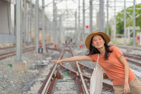 亚洲妇女是旅游者乘火车或电在铁路上旅行城市终点站乘坐电线杆塔和缆乘坐公共交通图片