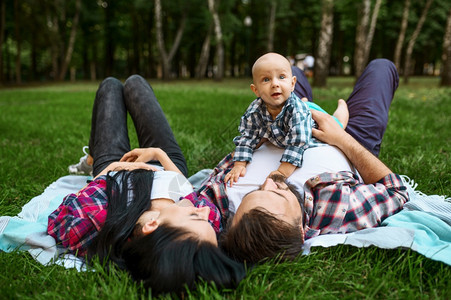 父母和亲在草地上与男孩坪父母森林中与孩子一起野餐家庭幸福母亲父和小婴儿在草地上休闲图片