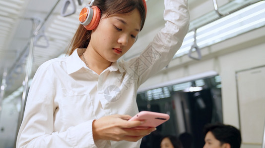 在公共火车上使用青年妇女移动电话城市生活方式交通概念图片
