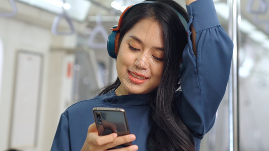 在公共火车上使用青年妇女移动电话城市生活方式交通概念图片