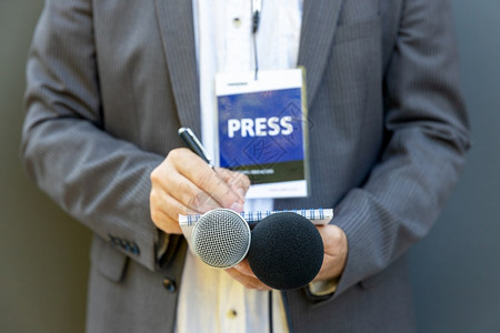 男记者参加新闻发布会或媒体活动手持麦克风写笔记图片