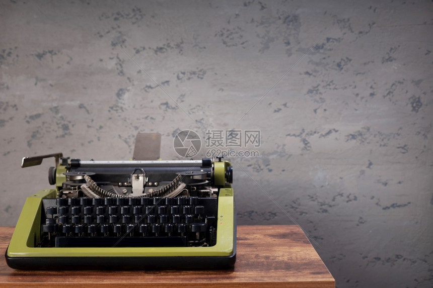 墙底表面附近木桌边的老旧打字机图片