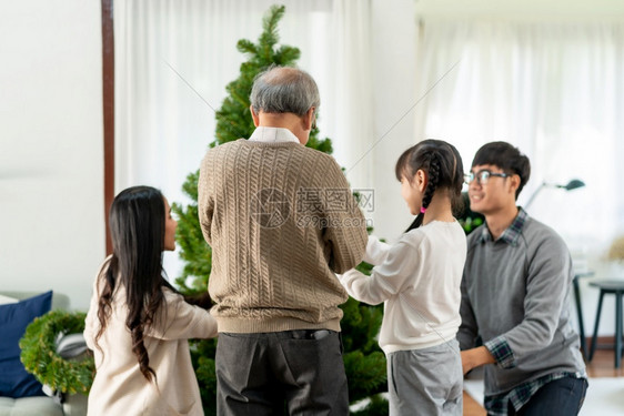 多代亚洲家庭装饰圣诞树爸妈女儿孩和祖父装饰圣诞树为快乐和节日的季问候做准备图片