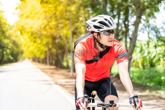 穿着运动服骑自行车运动员在农村公路上骑行欣赏风景图片