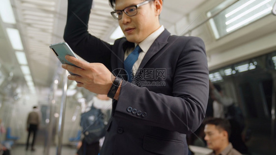 商人在公共火车上使用移动电话图片