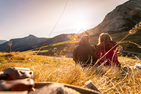 穿着运动服的夫妇享受山上日落坐在地上享受风景奥地利阿尔卑斯图片