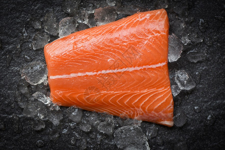 冰和黑石背景的新鲜生鲑鱼牛排图片