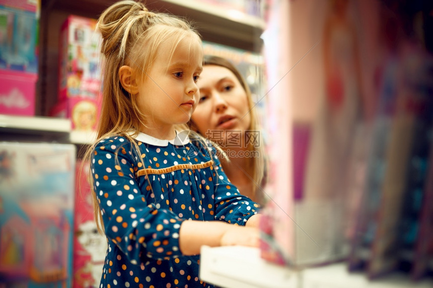 妈和可爱的女儿在玩具店展台附近快乐的童年家庭在商店买东西妈和小女孩在玩具店里买一个娃玩具店图片