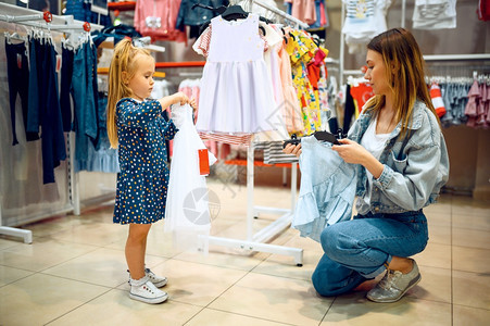 母亲和小婴儿在商店中挑选衣服图片