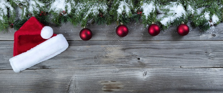 圣诞快乐关于生锈天然木本底的圣诞概念以及传统的球装饰品和圣诞帽的节日装饰品和圣诞帽图片