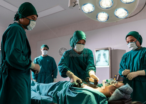 手术室外科医生和护士在手术室外科时使用防病器对人进行治疗而病人对突然心脏逮捕有问题医疗外科手术概念图片