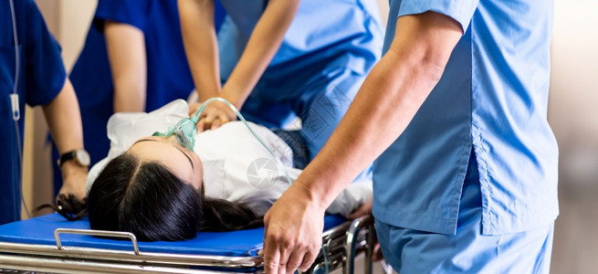 医疗队用氧气罩对严重受伤的病人进行心肺复苏检查同时将轮椅担架床推到手术室背景图片