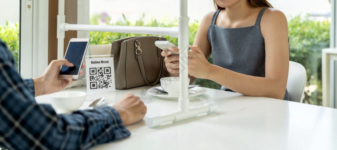 亚洲全景客户扫描QR码在线菜单新冠19大流行后顾客坐在餐厅新的正常生活方式社会偏移桌上图片