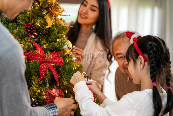 多代亚洲家庭装饰圣诞树爸妈女儿孩和祖父装饰圣诞树为快乐和节日的季问候做准备图片