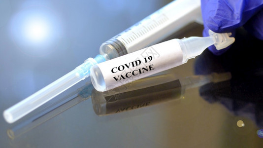 医务人员用蓝色外科手术套将贴上紧拿着一小瓶科罗纳疫苗图片