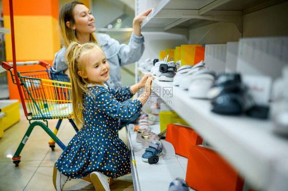 母亲和女孩在商店挑选鞋子图片