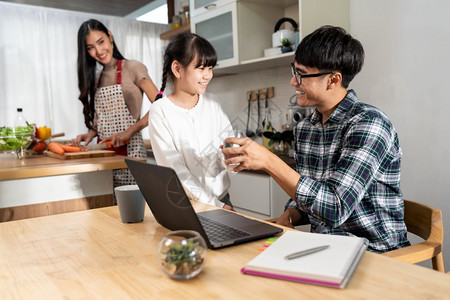 亚洲小女孩在厨房做电脑笔记本和妈烹饪时向父亲供水在家工作与新冠19隔离幸福家庭团圆概念图片