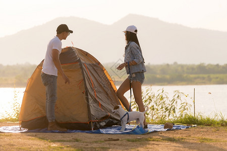 年轻的亚洲成人夫妇在湖边搭建帐篷露营图片