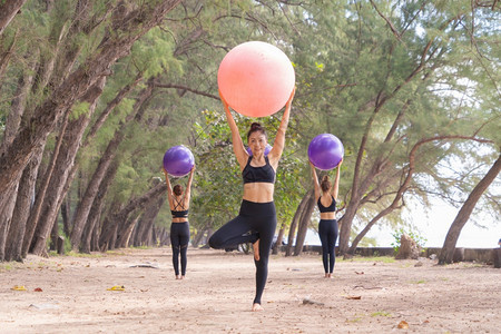 参加瑜伽班俱乐部的亚洲妇女群体在自然海滩树木和户外沙滩上进行锻炼和瑜伽参加运动和娱乐概念图片