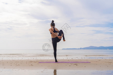 一名在瑜伽班俱乐部的亚洲妇女在自然海滩和滨户外从事运动和娱乐概念方面的锻炼和瑜伽图片