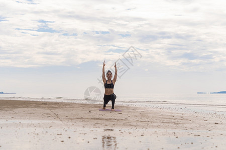 一名在瑜伽班俱乐部的亚洲妇女在自然海滩和滨户外从事运动和娱乐概念方面的锻炼和瑜伽图片