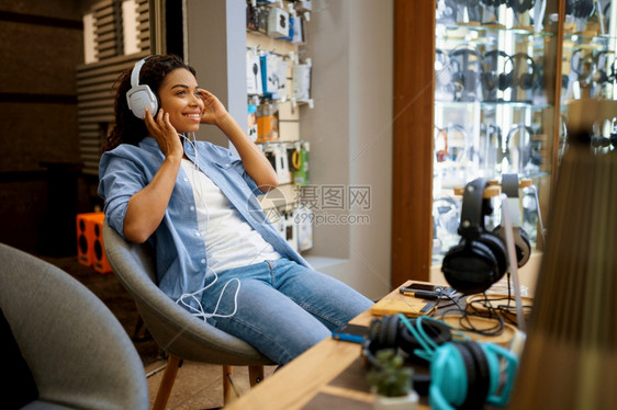 在音频商店乐风扇中尝试耳机的顾客在音乐店背景上用耳机展示在多媒体沙龙购买在音乐店里尝试耳机的顾客在音频商店中尝试耳机的顾客图片