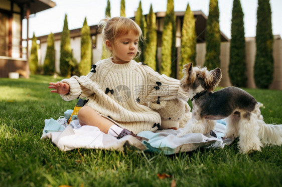 小孩和狗狗坐在后院的草坪上图片