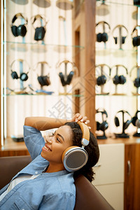听耳机店音乐的快妇女听音店背景有耳机的展示多媒体沙龙买家的快乐妇女听音耳机店的快妇女图片