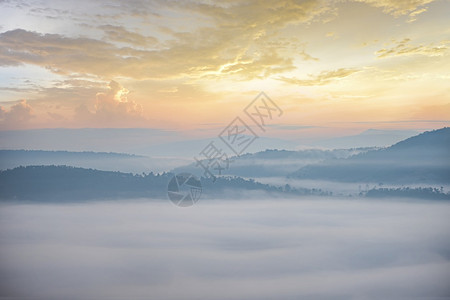 清晨美丽的日出烟雾覆盖乡村冬季的山地背景图片