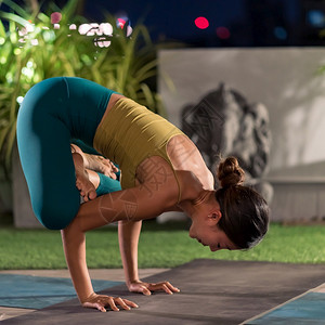 穿着运动裤的亚裔女穿运动裤的内在城市被禁闭期间单独练习瑜伽她的背景是夜间城市色照明设计健康的生活方式概念图片