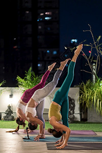 一群穿运动裤的亚洲女穿运动裤在城市封锁期间练习瑜伽在城市风景照明之夜背中她们与距离很远的外表相隔图片