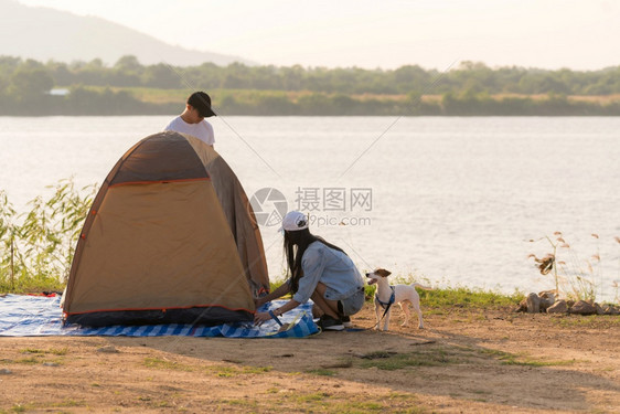 年轻的亚洲成人夫妇在湖边搭建帐篷露营图片