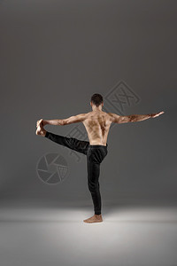 肌肉男瑜伽在工作室进行伸展运动灰色背景强壮的人在工作室进行伸展运动图片