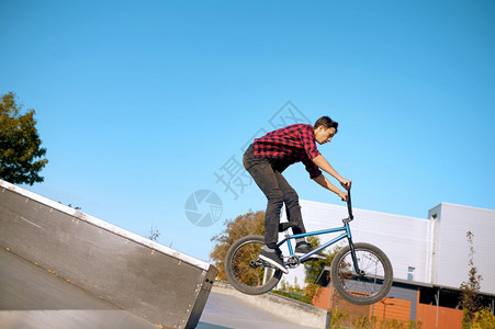 Bmx骑自行车者在楼梯上耍花招在滑板场上训练青少年极端自行车运动危险的自行车运动危险的街头骑车在夏季公园骑自行车Bmx骑自行车者图片