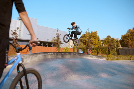 滑板车跳上斜坡滑板车培训极端自行车运动危险循环街头骑车青少年在夏季公园骑自行车图片