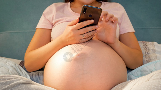 孕妇晚上躺在床上使用手机图片
