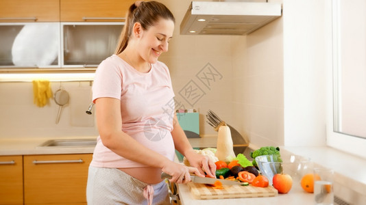 在厨房和做家务时等待婴儿烹饪的微笑年轻妇女怀孕期间健康生活方式和营养概念怀孕期间健康生活方式和营养概念图片