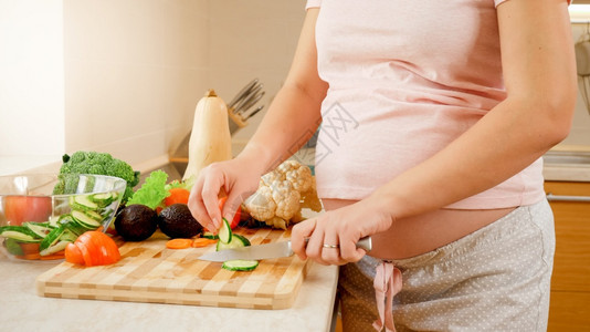 在家厨房做沙拉和吃新鲜黄瓜孕期健康生活方式和营养概念图片