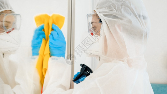 使用化学洗涤剂和消毒家具的比阿扎德防护衣洗房中的细菌学家或清洁工人使用化学洗涤剂和消毒家具的比阿扎德防护衣洗房中的细菌学家或清洁图片