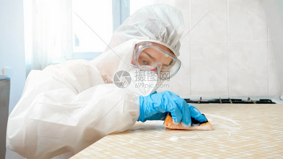 家庭主妇戴医用手套面罩防护服清洁和用化学洗涤剂海绵清厨房桌台和图片