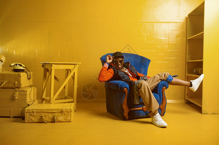 歌舞手唱脱舞表演Rapper与黄色音调一起坐在演播室的椅子上图片