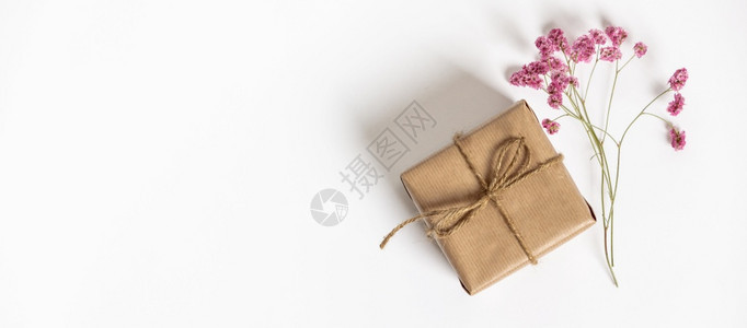 装有Kraft纸和粉红色花朵的礼品盒放在白色背景上平整的板样式复制文本空间图片