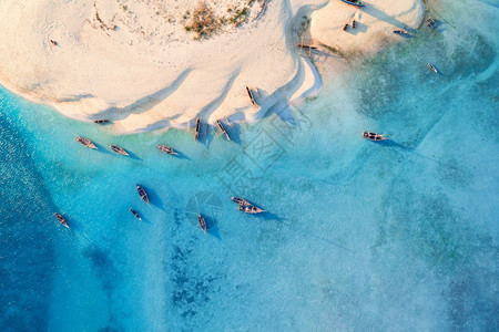 热带海岸的渔船空中观察日落时有白沙滩夏季在非洲桑给巴尔旅游有船艇绿棕榈树清蓝水的风景图片