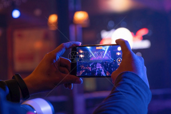手握智能机在迪斯科酒吧表演音乐节娱夜生活动图片