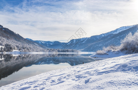 古时冬季风景反射湖雪树和山丘图片